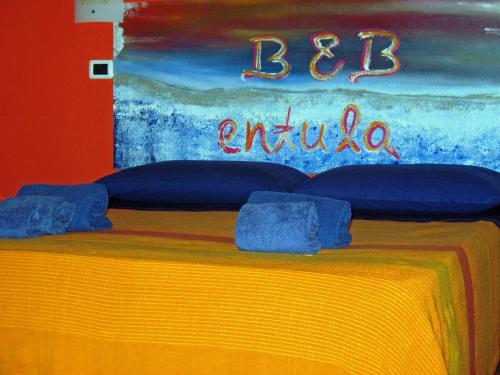 a bed with blue pillows in front of a painting at Entula in Àrbatax