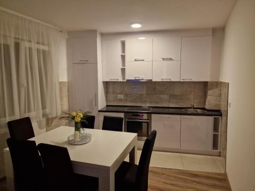 a kitchen with a table and chairs and a kitchen with white cabinets at Stan na dan, Loznica in Loznica