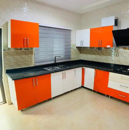 uma cozinha com armários laranja e branco e um lavatório em Apple Royal Apartments em Acra