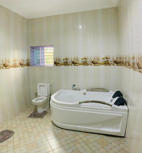 uma casa de banho branca com uma banheira e um WC em Apple Royal Apartments em Acra