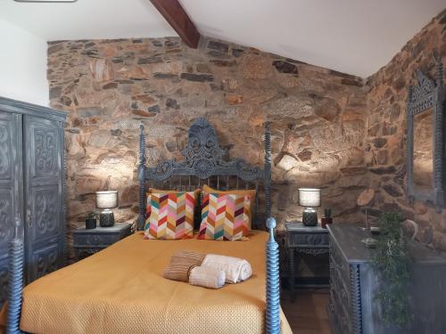 a bedroom with a bed in a stone wall at Ribança Village in Destriz