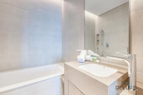 ein weißes Badezimmer mit einem Waschbecken und einer Badewanne in der Unterkunft Remarkable 1BR at The Address Residences in JBR by Deluxe Holiday Homes in Dubai