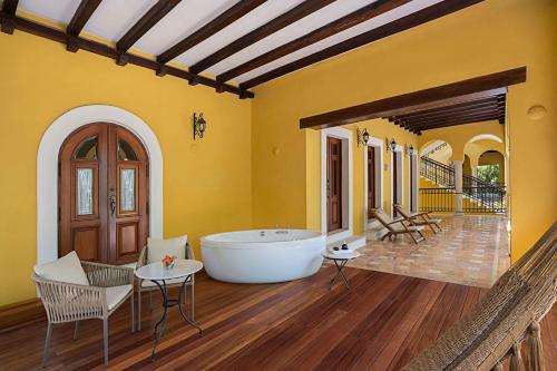 a large bathroom with a tub and a table and chairs at Hacienda Xcanatun, Angsana Heritage Collection in Mérida