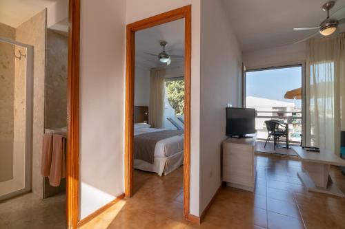 プラヤ・デル・イングレスにあるApartamentos Montemayorの鏡付きのベッドルーム(ベッド1台、テレビ付)