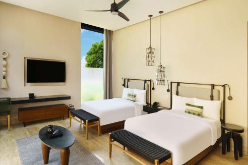 two beds in a room with a tv at Hacienda Xcanatun, Angsana Heritage Collection in Mérida
