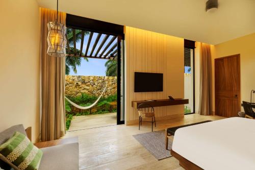 a bedroom with a bed and a desk and a television at Hacienda Xcanatun, Angsana Heritage Collection in Mérida