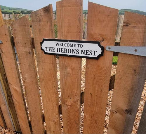 a sign on a fence that reads welcome to the helords nest at The Galloway Steading - The Herons Nest, secure garden and with Hot Tub and Fire Pit in Glenluce