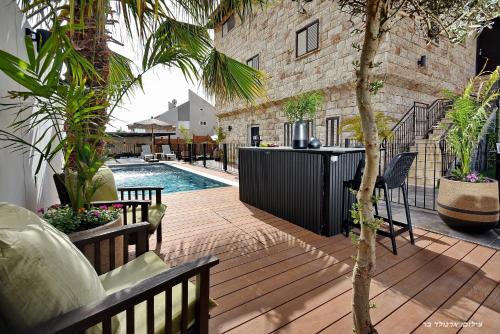 eine Terrasse mit einem Pool und einer Palme in der Unterkunft פנינת עוז - מתחם נופש יוקרתי in Oshrat