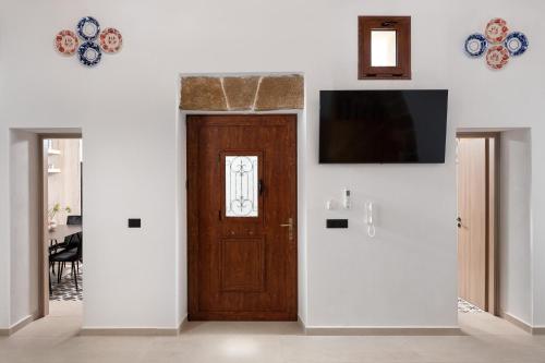 a room with a wooden door and a television on a wall at Antica Casa Dei Nonni in Archangelos