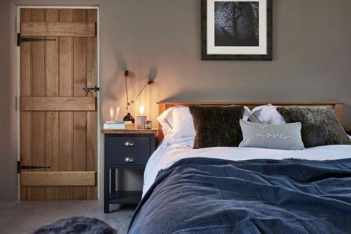 a bedroom with a bed with a blue blanket and a door at The Barn - Georgeham North Devon in Braunton