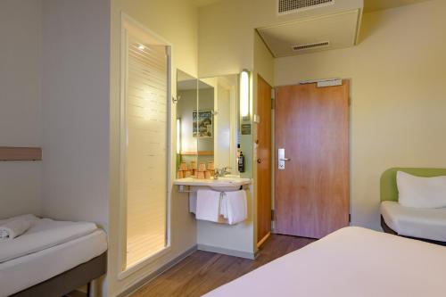a bedroom with a bed and a sink and a mirror at ibis budget Hotel Luzern City in Luzern
