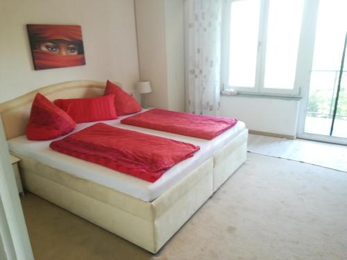 een groot bed met rode kussens in een slaapkamer bij Gaestehaus Jagsttalblick in Langenburg