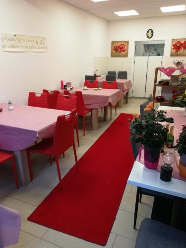 ein Esszimmer mit Tischen, roten Stühlen und roten Matten in der Unterkunft Gaestehaus Jagsttalblick in Langenburg