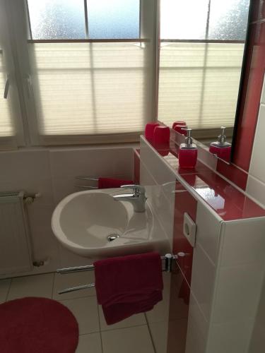 a bathroom with a white sink and red towels at Gaestehaus Jagsttalblick in Langenburg