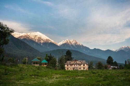 una casa en un campo con montañas en el fondo en LohonoStays Villa Hill Retreat, en Pahalgām