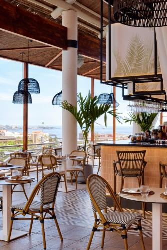 a restaurant with tables and chairs and a view of the ocean at Melia Jardines del Teide - Adults Only in Adeje