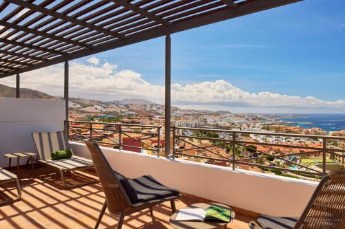 a balcony with chairs and a view of the city at Melia Jardines del Teide - Adults Only in Adeje