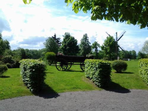 a horse drawn carriage in a park with bushes at Zur Windmühle Restaurant - Hotel in Beckum