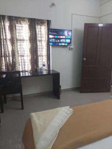 um quarto com uma cama, uma secretária e uma janela em Padmatheertham Inn em Varkala