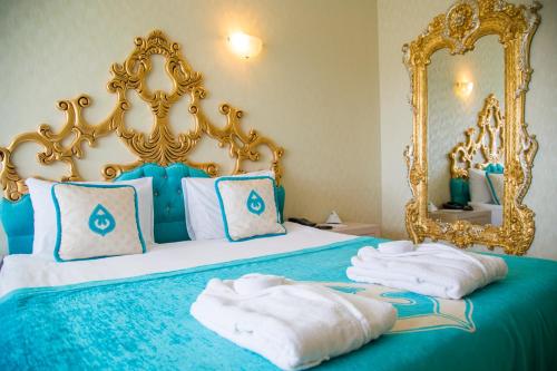 Daima Biz Hotel - Dolusu Aquapark Access في كيمير: غرفة نوم بسرير ازرق اطار ذهبي