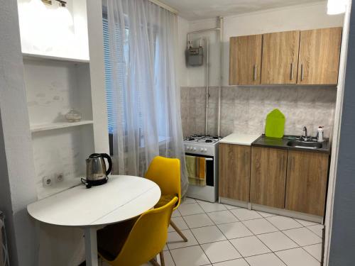 a small kitchen with a white table and yellow chairs at Ухоженная и уютная квартира!!! in Tiraspol