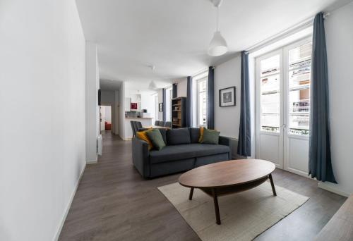 a living room with a couch and a table at Le Brit - Grand appartement design, 3 chambres, centre ville in Vichy