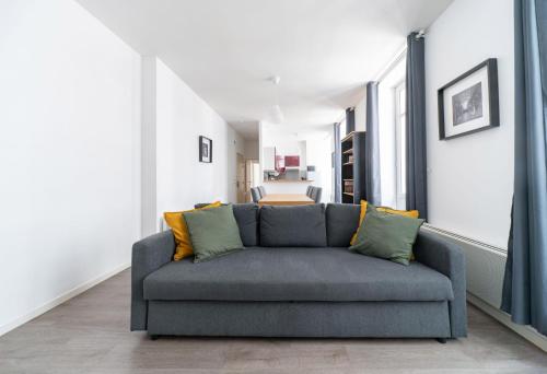 a living room with a gray couch in a room at Le Brit - Grand appartement design, 3 chambres, centre ville in Vichy