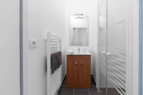 une salle de bain avec un lavabo et un miroir dans l'établissement Le Brit - Grand appartement design, 3 chambres, centre ville, à Vichy