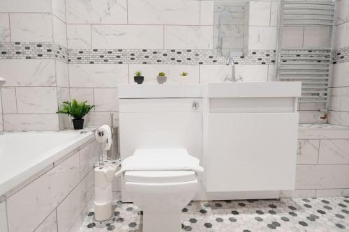 a white bathroom with a toilet and a sink at Prenton House, 3BR Close to Liverpool in Birkenhead