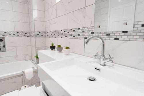 a white bathroom with a sink and two plants at Prenton House, 3BR Close to Liverpool in Birkenhead