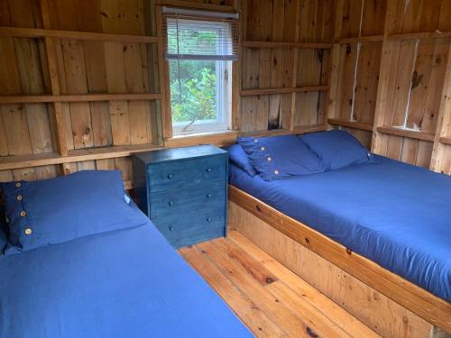 Habitación con 2 camas en una cabaña de madera en Centre nautique de l'Istorlet en Havre-Aubert