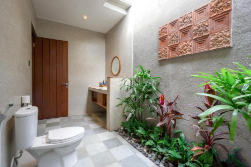 een badkamer met een toilet en een aantal planten bij De Rekun Ubud in Ubud