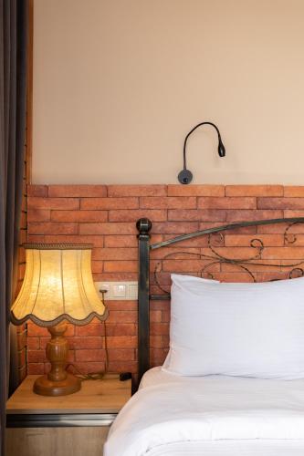a bed with a lamp next to a brick wall at Honeymoon Apartments in Old Tbilisi in Tbilisi City
