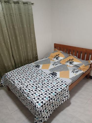 um quarto com uma cama com um edredão e almofadas em EJA TRANSIENT HOUSE em Bacolod
