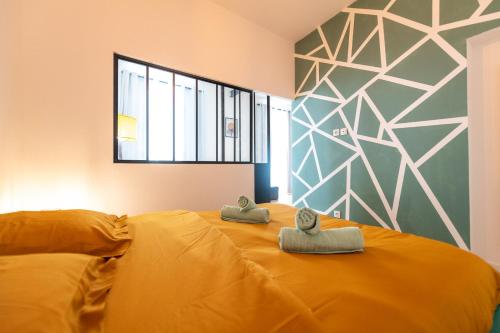 Un dormitorio con una gran cama amarilla con toallas. en KASA ARTY - Tout équipé - Agréable et confortable en Saint-Étienne