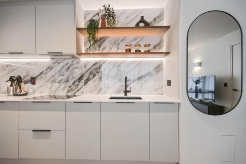 a white kitchen with a sink and a mirror at Bow Lane by Aeria Apartments in London
