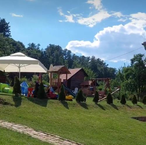 um quintal com um parque infantil e um guarda-chuva em Palanačka Avlija 3 em Ripanj