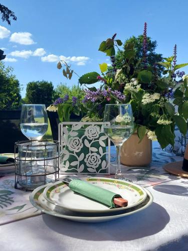a table with a plate and wine glasses and flowers at Apartamenti Dundaga XXL in Dundaga