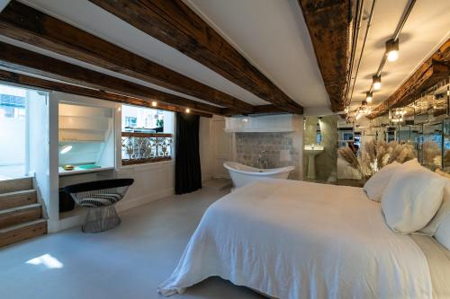 Exceptional Stay in Jordaan Area في أمستردام: غرفة نوم بسرير ابيض وحوض استحمام
