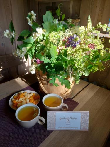 a table with two cups of tea and a bouquet of flowers at Apartamenti Dundaga XXL in Dundaga