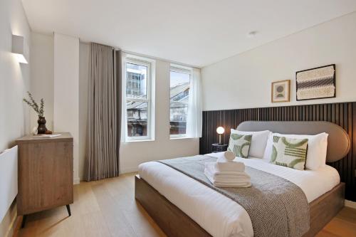 a bedroom with a large bed and two windows at Bow Lane by Aeria Apartments in London