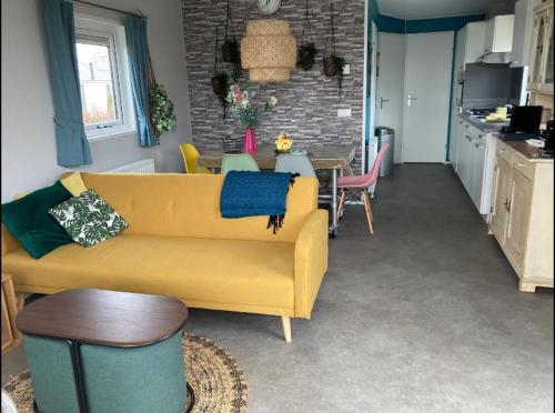 a living room with a yellow couch and a table at Chalet 561 op Recreatiepark De Wielen in Sint Maarten