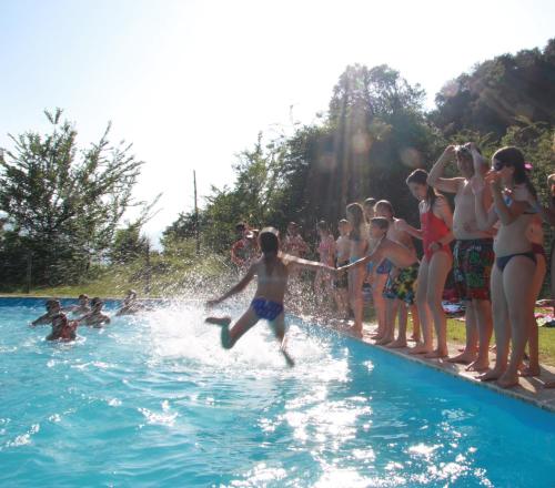 un niño pequeño saltando a una piscina en Casa de colònies La Cadamont, en Sant Joan les Fonts