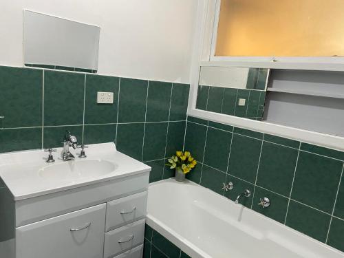 a green tiled bathroom with a sink and a bath tub at Rose House in Deer Park