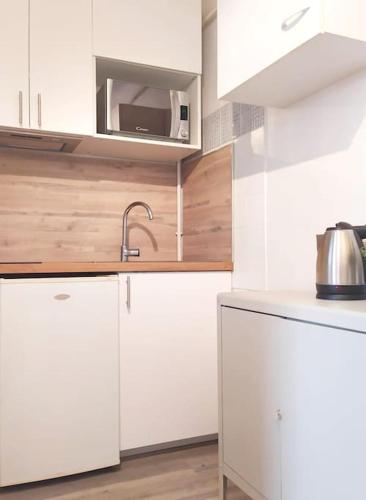 une cuisine blanche avec un évier et un micro-ondes dans l'établissement Appartement climatisé au cœur de Montpellier, à Montpellier
