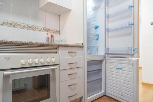 cocina con armarios blancos y nevera abierta en Luminoso Madrid Javalambre, en Madrid