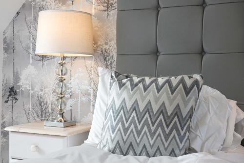 a bed with a pillow and a lamp on a night stand at Loughton House - Central Location - Free Parking, Private Garden, Super-Fast Wifi and Smart TVs by Yoko Property in Milton Keynes