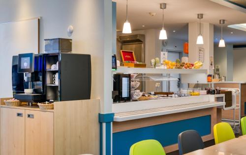 a restaurant with a counter with yellow chairs at ibis budget Hotel Luzern City in Luzern