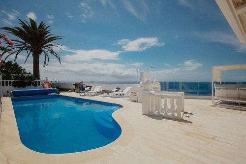 una piscina con sillas y vistas al océano en Villa Blanca, en Callao Salvaje