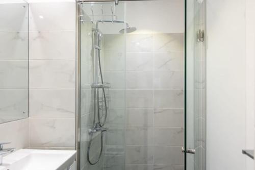 um chuveiro com uma porta de vidro ao lado de um lavatório em Plush 1 Bedroom/Guest Washroom @The Lennox Airport em Acra